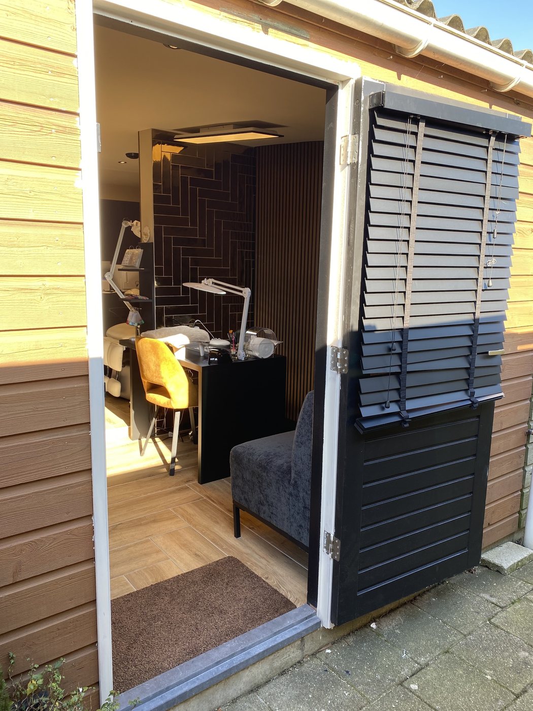 De openstaande deur van Rory's studio, met zicht op de nageltafel en een fauteuil